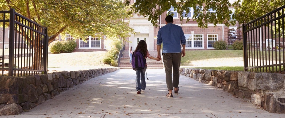 parent holding kid's hand at school