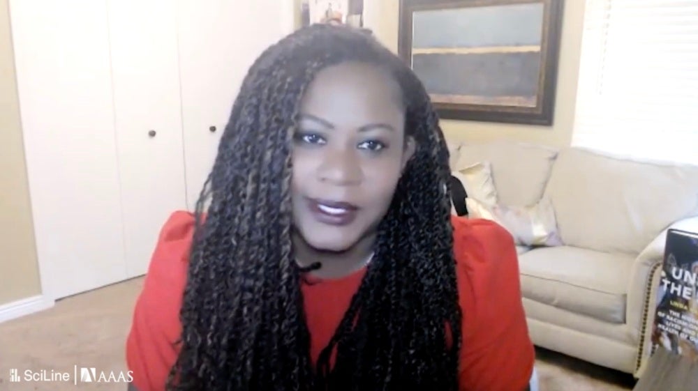 Dr. Rachel Hardeman sits in a beige room with long black hair and a red outfit. She is in an interview about the racial inequities in pregnancy-related deaths.